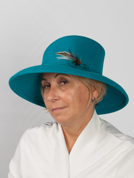 Side view of a large brimmed turquoise wool felt hat with felt band around crown and feather detail to the side