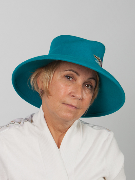 Side view of a large turquoise wide-brimmed felt hat with felt band around crown and feather detail