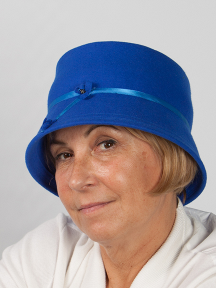 Side view headshot of a royal blue wool felt bucket hat with narrow satin band around crown and band detail to the frontt and