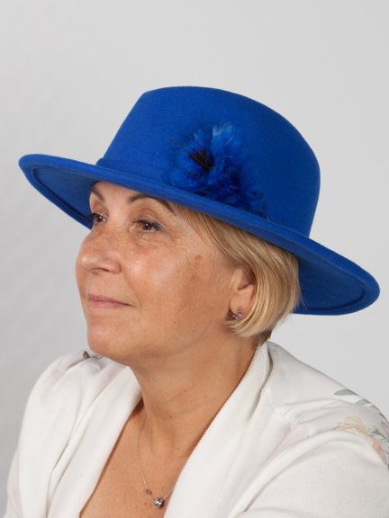 Side vew headshot of a royal blue fedora wool felt hat with a plume on the side.
