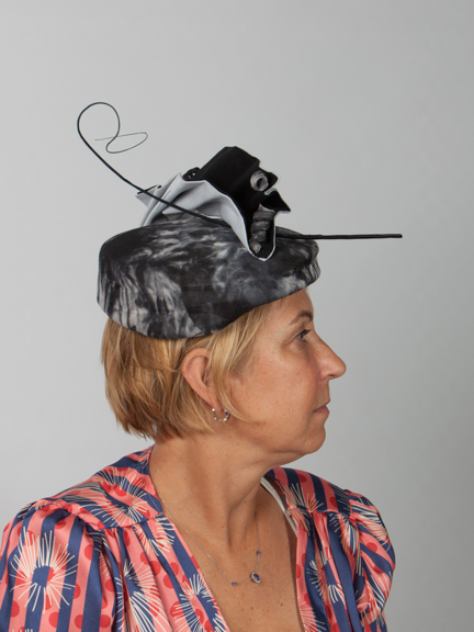 Side view of a dark navy and white occasion hat with navy quill and nmatching fabric detail on top
