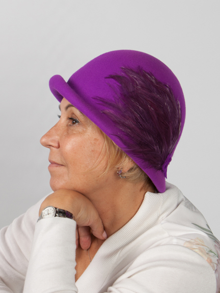 Side view headsho of a wool fushia felt hat with feather pad on the sidead