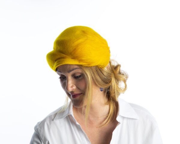 Side view of yellow wool felt hat with feather detail to theside